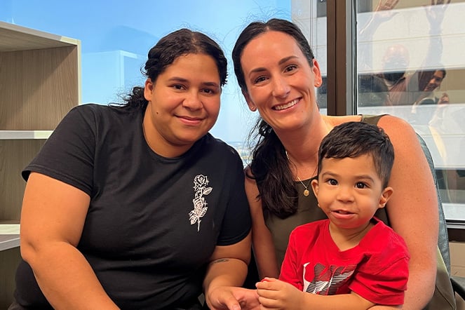 a toddler sitting with two adult women