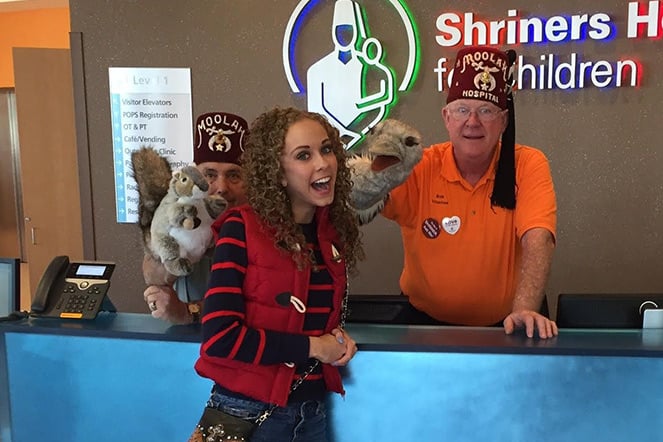 Elliana laughs with two Shriners and sock puppets