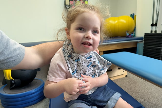 A smiling toddler in a physical therapy room