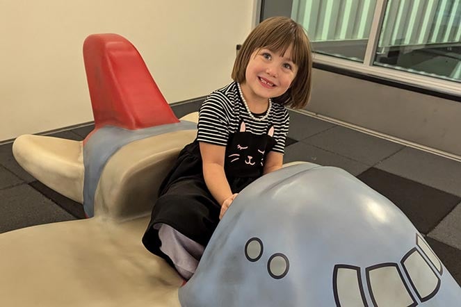 female casting patient sitting on toy airplane
