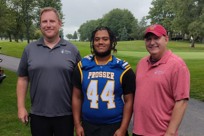 an athlete in a football jersey with the number 44 standing between two smiling men