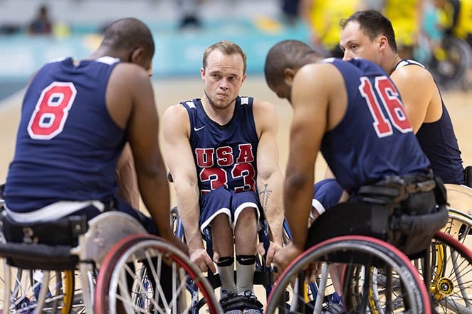four wheelchair para athletes in huddle on basketball court
