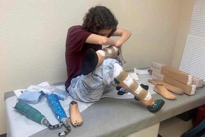 Grace putting on her rock climbing prosthetic legs
