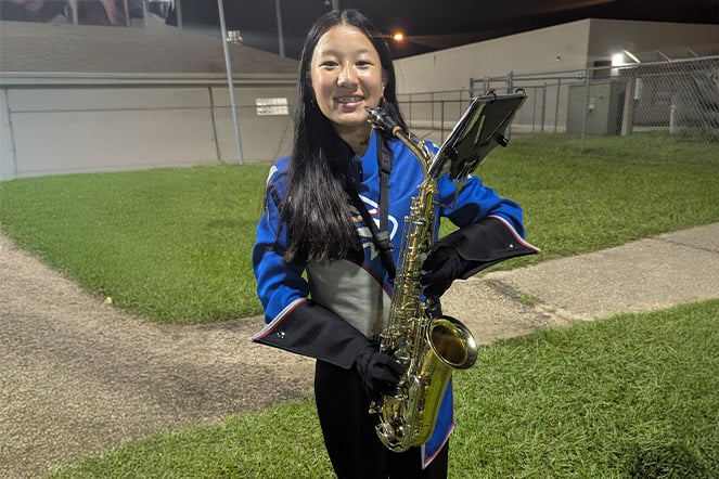 a child in a marching band uniform holding a saxaphone