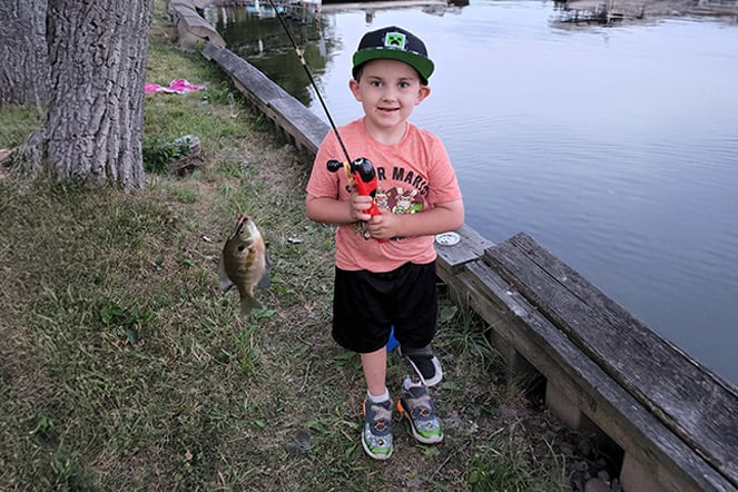 a child with a prosthetic leg holding a fish from a fishing pole