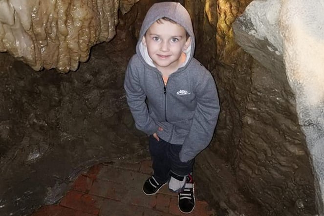 a child with a prosthetic leg smiling in a cave