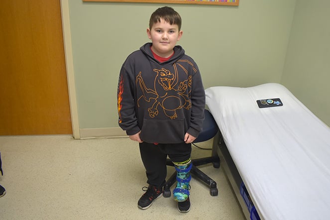 a child with a prosthetic leg smiling in an exam office