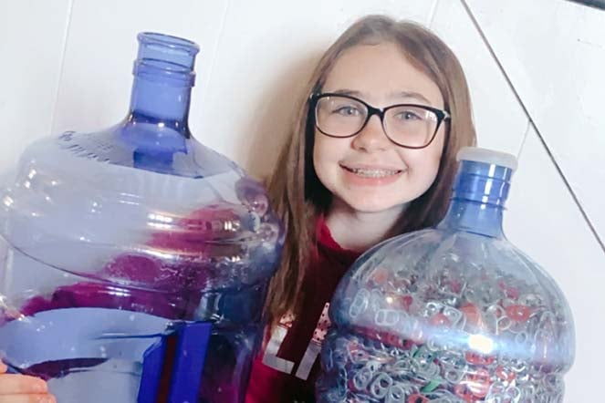Maddie holding container of can tabs