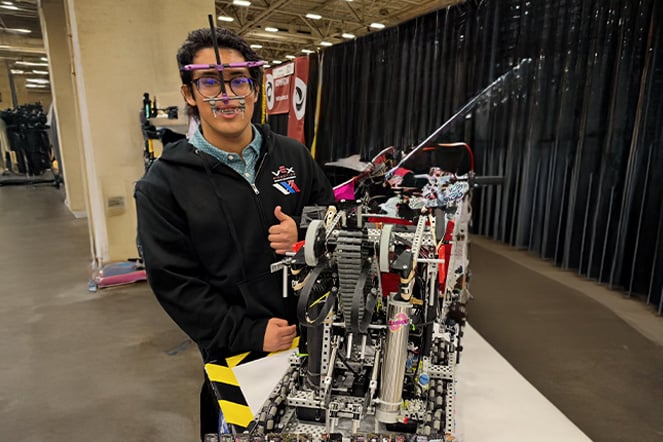 a teenager wearing a maxillary distractor smiling next to a robot