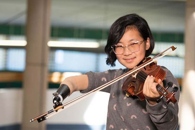 Momo playing violin with prosthetic arm