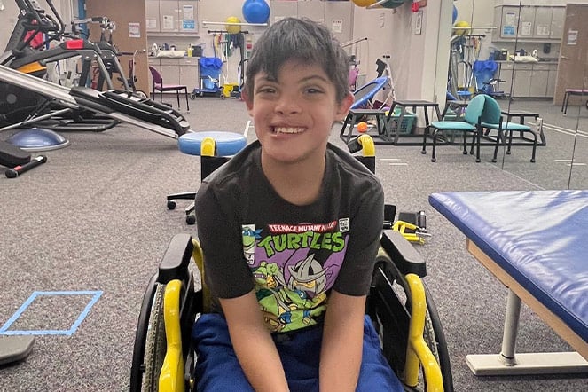 a smiling child in a room surrounded by exercise equipment