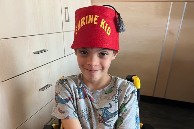 a child wearing a fez that reads "Shrine Kid"