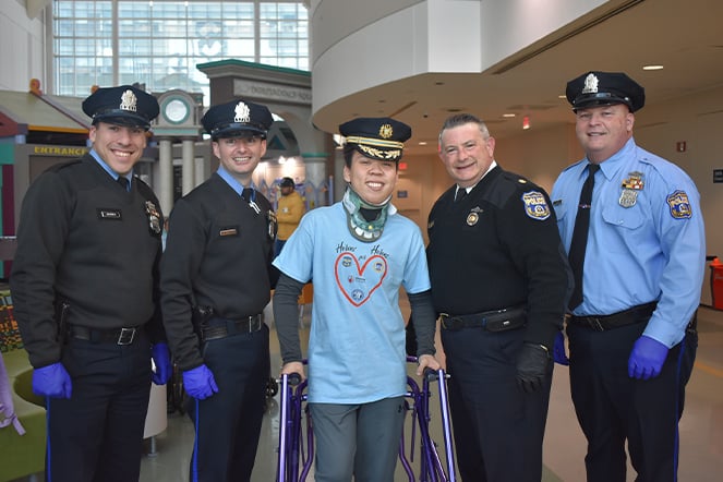 A teenager in a walker and neck brace with four police officers