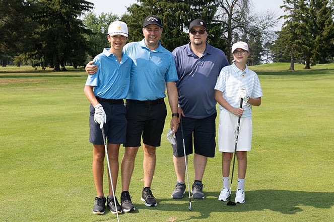 a group photo of four golfers on a golf course
