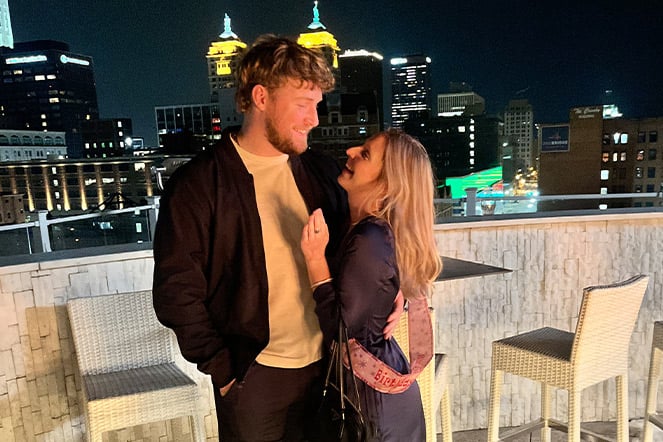 a man and a woman looking at each other with affection in front of an evening city skyline