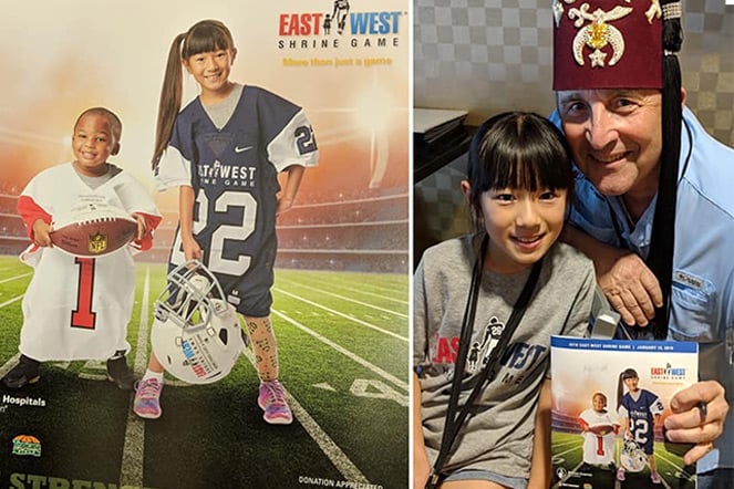 a young child and a man wearing a fez stand next to a banner displaying the young child in a large football jersey with another child. The banner has the East West Shrine Bowl Logo.