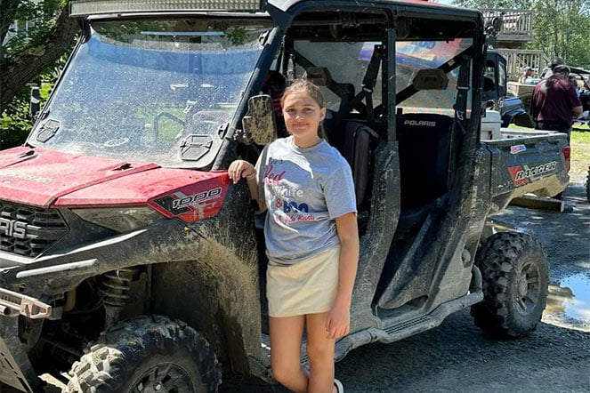 Patient stands next to ATV at fundraising event