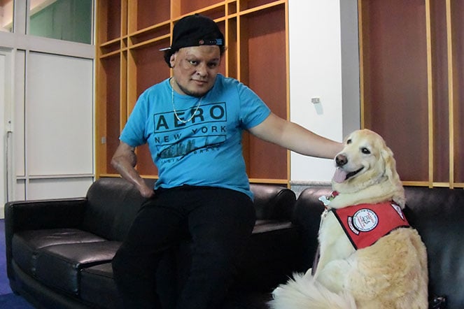 Patient Josue petting a golden retriever dog.