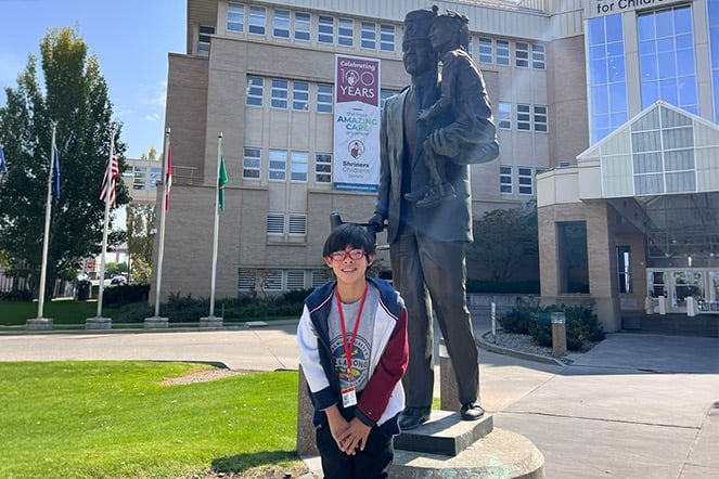 a child smiling next to a statue