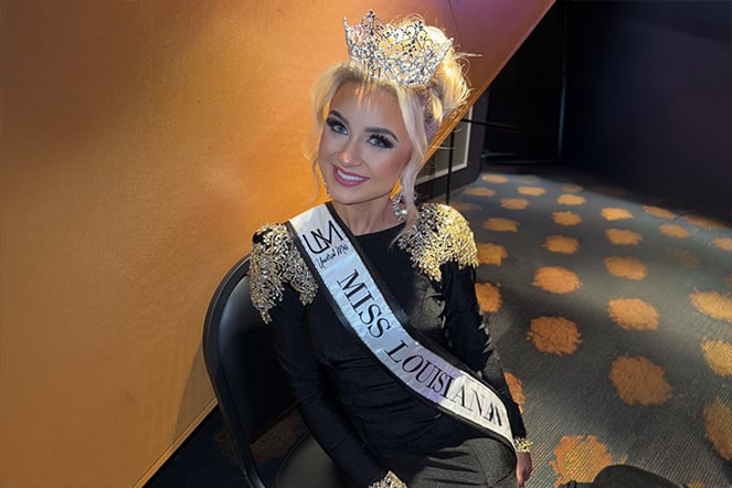 Patient Anna in a black pageant gown wearing a tiara and a sash that reads "Miss Louisiana"