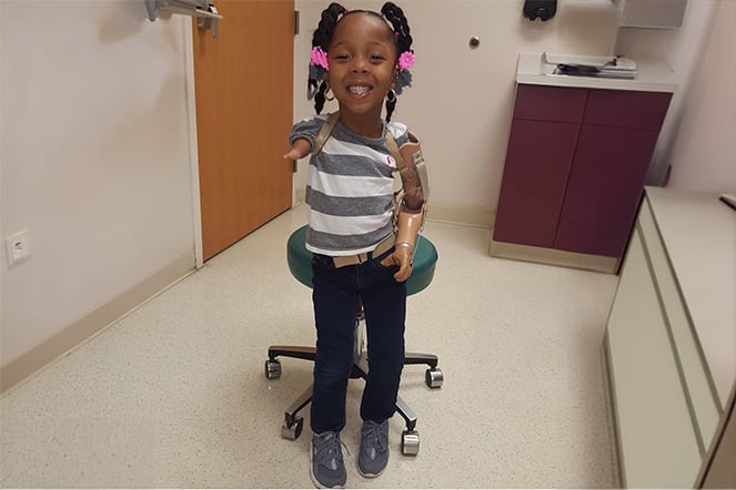 Prosthetic patient smiling and standing in an examination room
