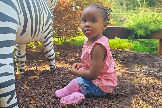 a toddler sitting in mulch in a garden