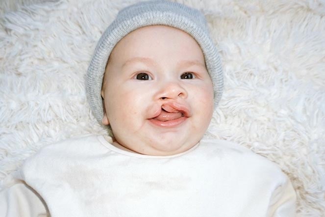 Saint dressed in white laying on white rug, smiling