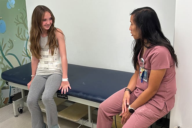 a child speaking to an adult in hospital scrubs