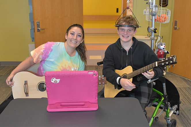 an adult and a teenager wearing a halo traction device holding guitars
