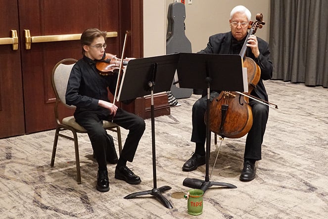 a teenager playing a violin next to an adult playing a cello