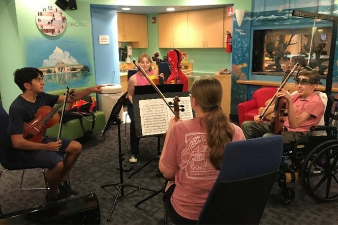 a string quartet led by a teenager in a halo traction device 