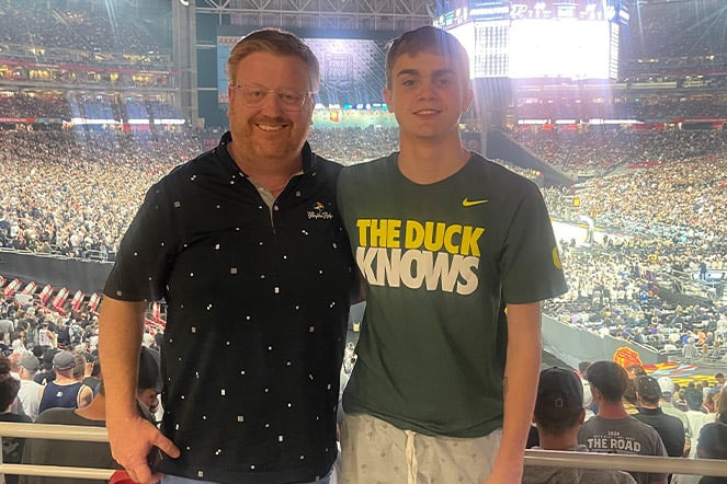 Scoliosis patient wearing a shirt that reads "The Duck Knows" smiling with their father
