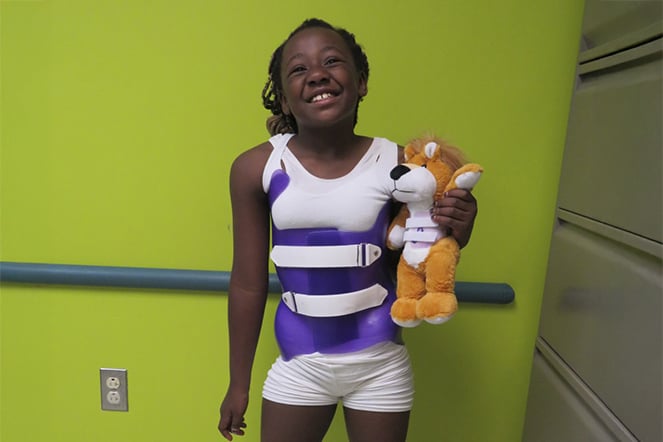 a patient wearing a back brace holding a teddy bear