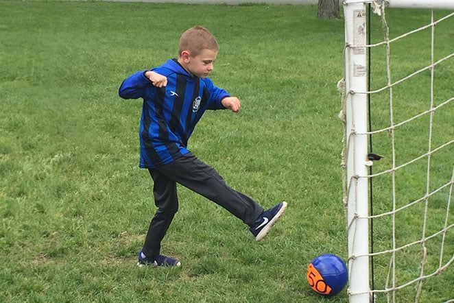 patient kicking soccer ball into goal