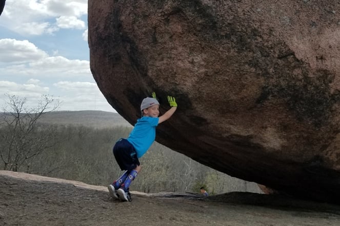 spina bifida patient playfully acting like they are pushing a boulder