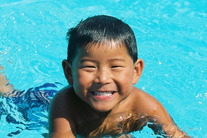 a smiling child swimming in a pool