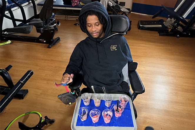 a child in a power chair with a tray full of cups of food