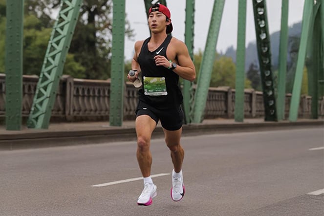an adult man running a race on a bridge