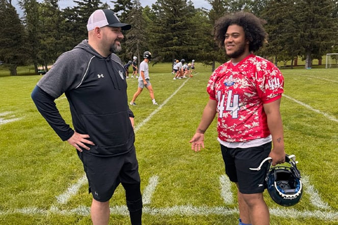 a football player speaking with a coach on a football field
