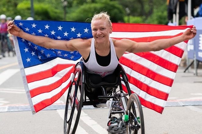 Susannah crossing finish line holding the American flag