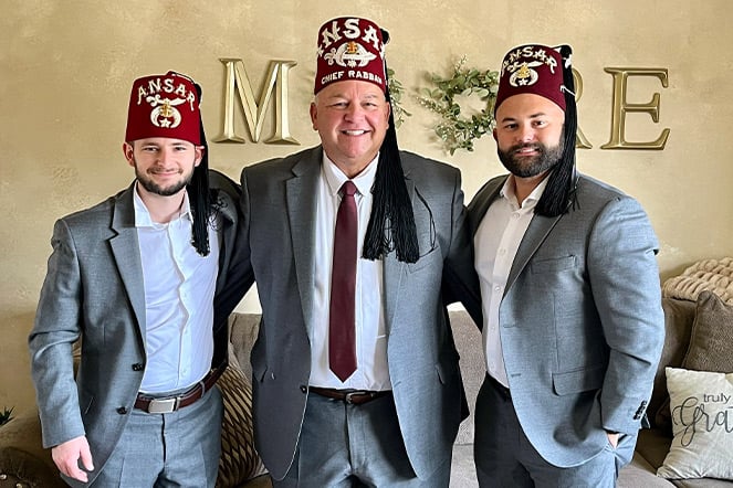 three men in suits and fezzes that read "Ansar"