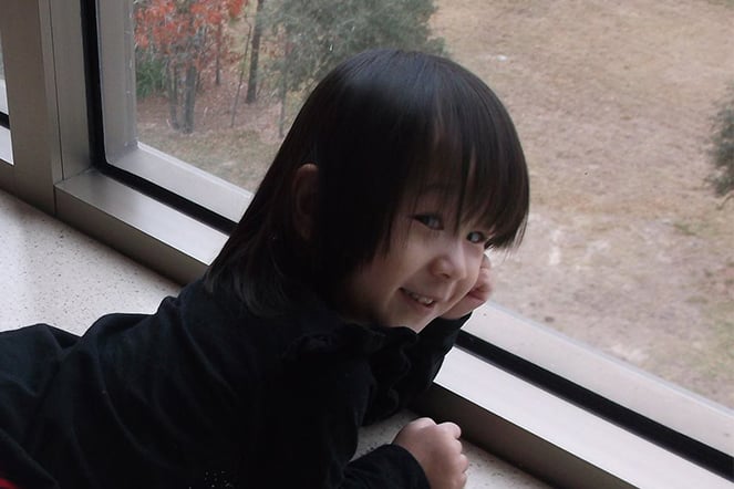 a smiling toddler looking out a window