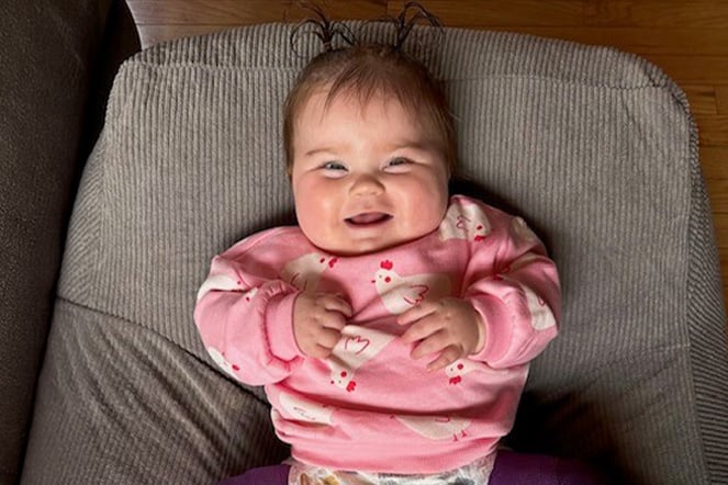 an infant laughing on a large seat cushion