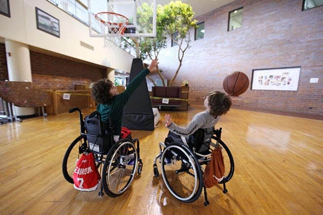 two young patients in wheelchairs playing basketball