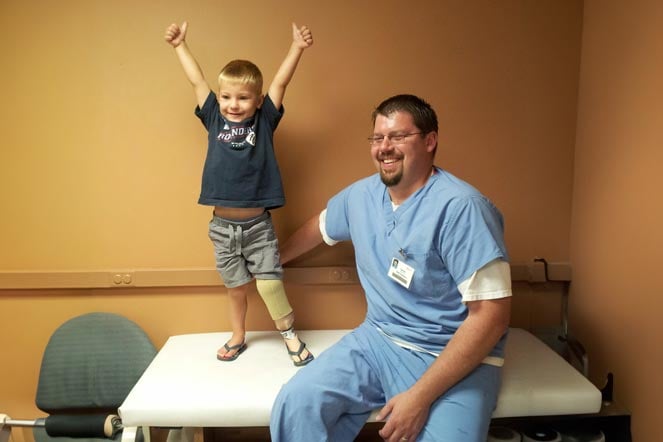 young Colton standing on examining table, with provider
