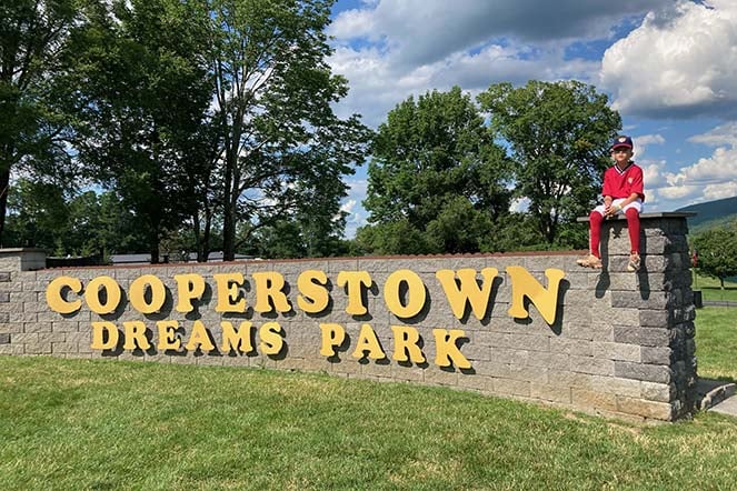 Zavi sitting on Cooperstown Dreams Park sign