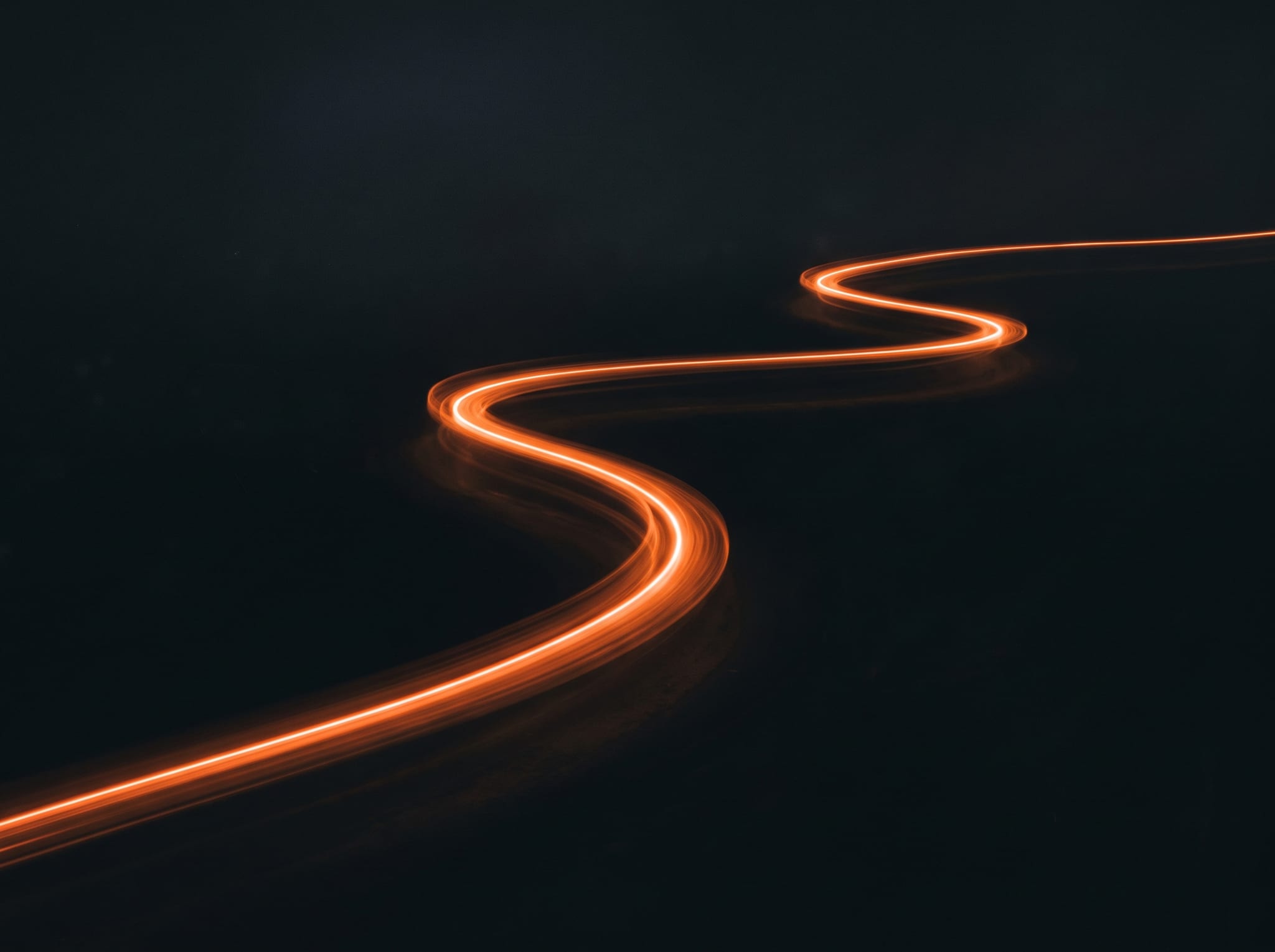 A single continuous ribbon of warm light flowing unbroken through darkness