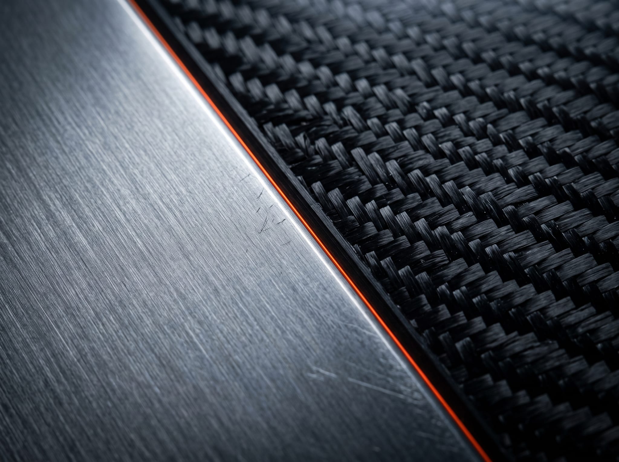 Brushed titanium meeting carbon-fibre weave at a precise machined edge