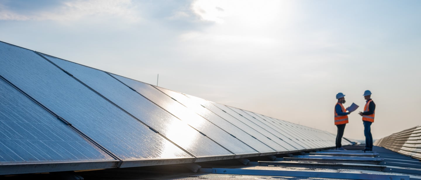 two workers in front of large solar panel installation