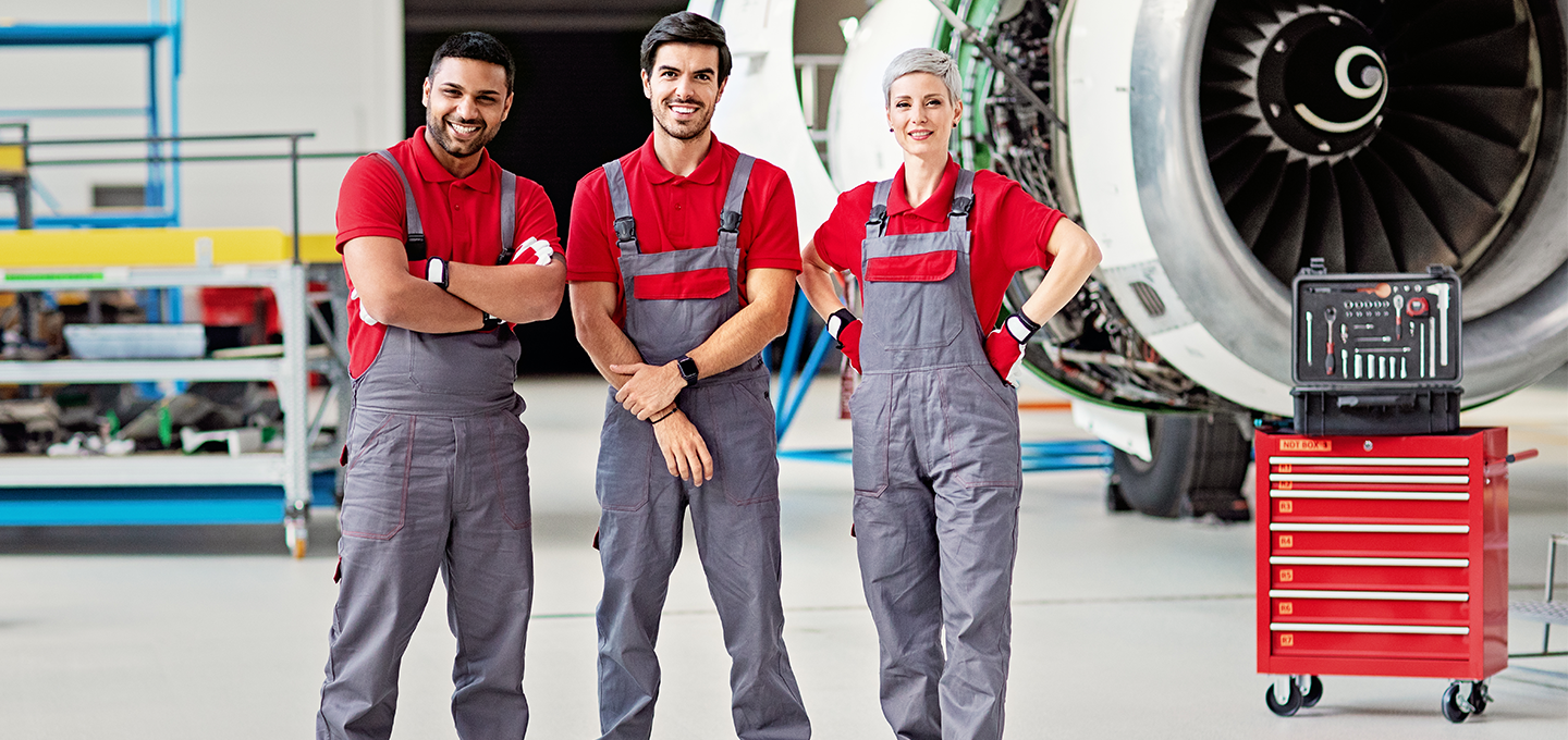 airplane hangar workers post in front of plane engine